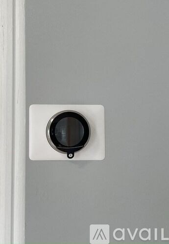 A white circular object is mounted on a grey wall.