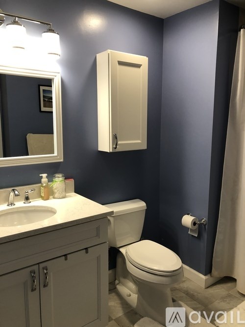 A bathroom with a toilet, sink, and mirror.