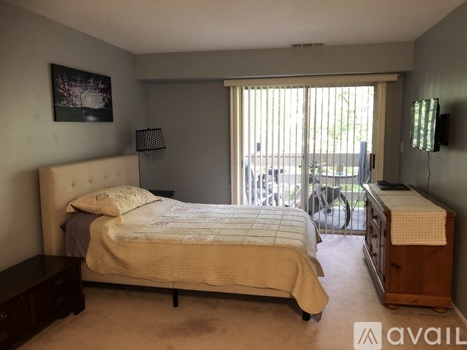 A bedroom with a large bed and a balcony with a bicycle.