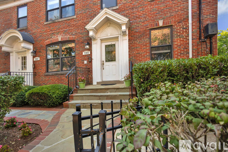 A red brick building with a white door and a no parking sign in front.