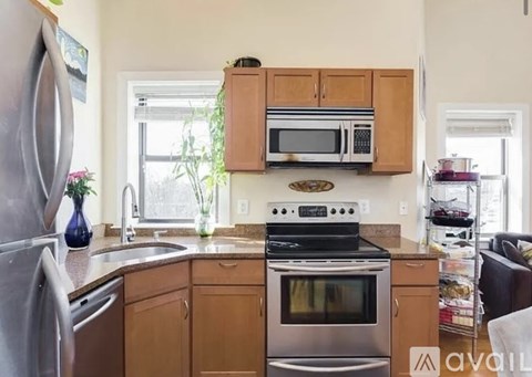 A kitchen with wooden cabinets and a stainless steel refrigerator.