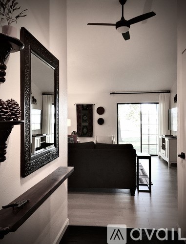 A living room with a black couch and a mirror on the wall.