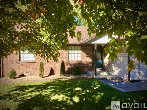 A house with a green lawn and trees in front of it.