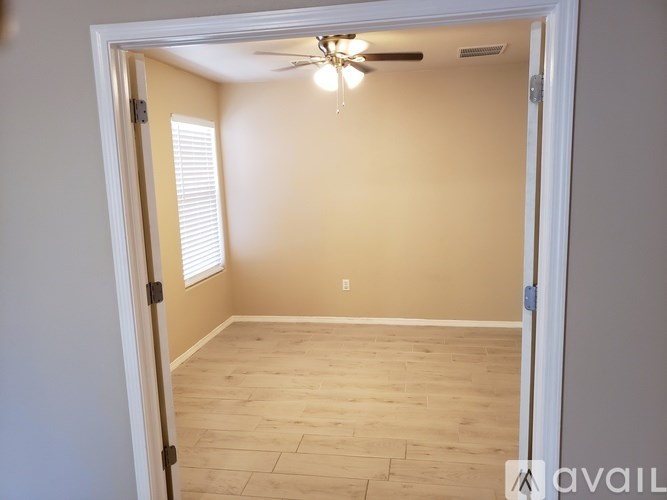 A room with a ceiling fan and wooden flooring.