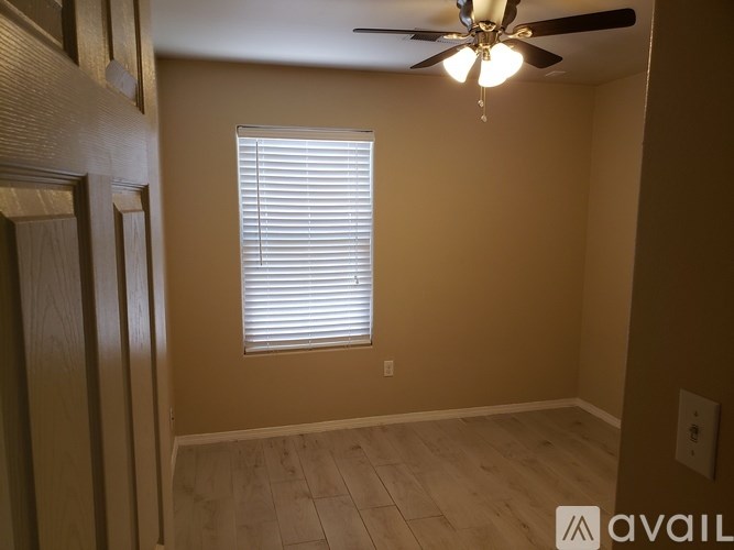 A room with a ceiling fan and a window with blinds.