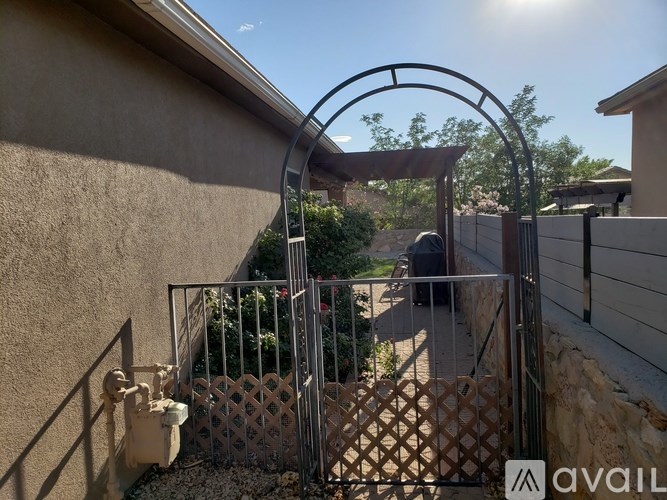 A metal gate with a lattice pattern leads to a patio.