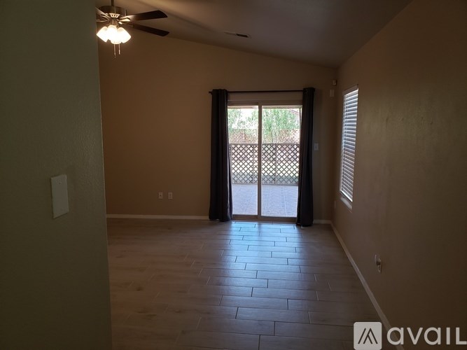 A room with a ceiling fan and sliding glass doors leading to a patio.