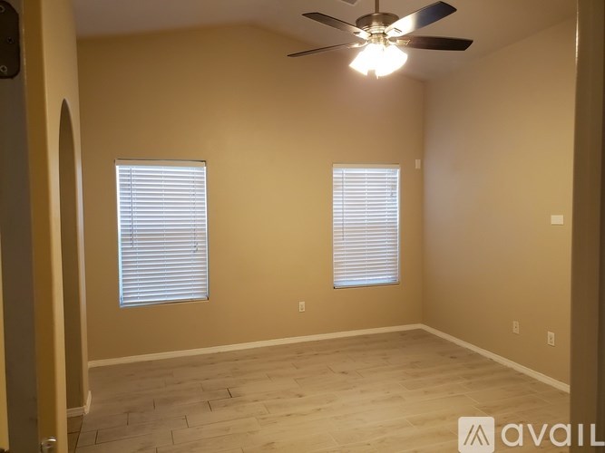 A room with a ceiling fan and two windows.