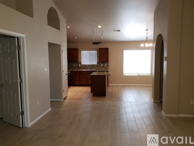 A spacious living room with a kitchen area in the background.