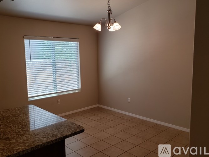 A room with a granite countertop and a window with blinds.