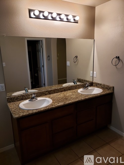 A bathroom with a granite countertop and two sinks.