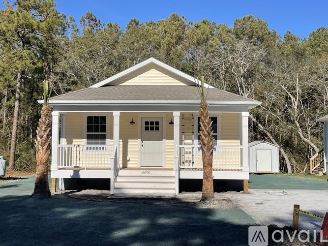 A small house with a porch and a tree in front.