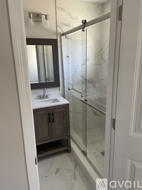A bathroom with a sink, mirror, and shower.