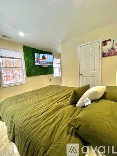 A bedroom with a bed, a window, and a wall-mounted TV.