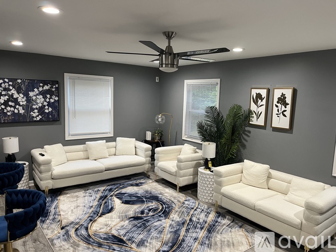 A living room with a white sofa set and a ceiling fan.