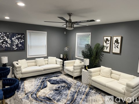 A living room with a white sofa set and a ceiling fan.
