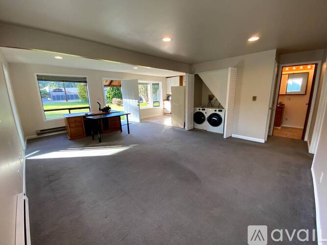 A spacious living room with a kitchen area in the background.