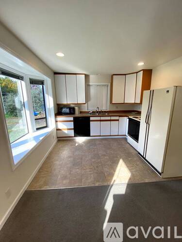 A kitchen with white cabinets and a refrigerator is available for rent.
