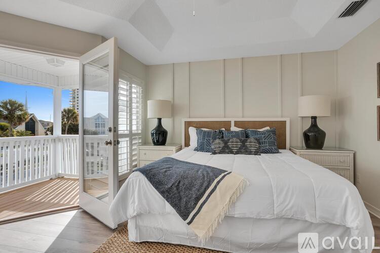 A bedroom with a large bed and a balcony with a view of the outside.