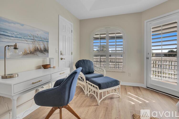 A room with a desk, chair, and a painting of a beach scene on the wall.