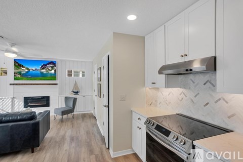 A modern kitchen with a stove top oven and a flat screen TV mounted on the wall.