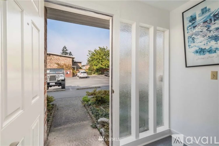 A view from inside a room looking out through a glass door to a street with cars and buildings.