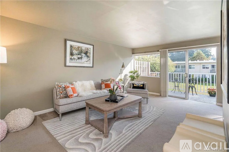 A living room with a grey couch, a coffee table, and a large window.