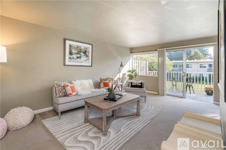 A living room with a grey couch, a coffee table, and a large window.