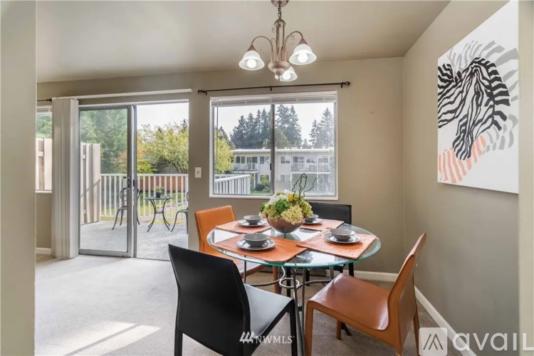 A dining room with a table set for two and a view of a deck outside.
