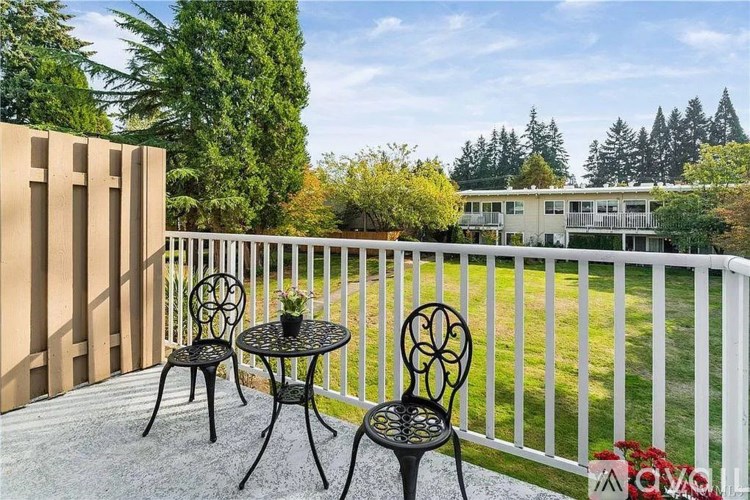 Two black chairs and a table are on a patio.