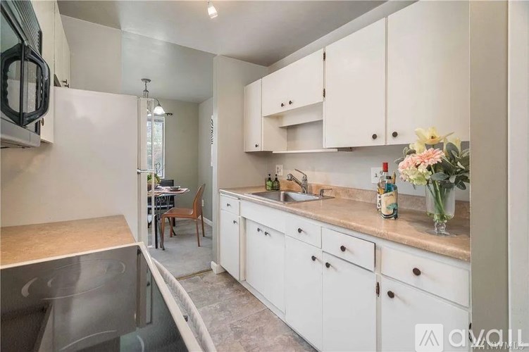 A kitchen with white cabinets and a marble countertop.
