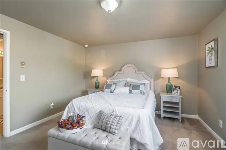 A bedroom with a large bed and two lamps.