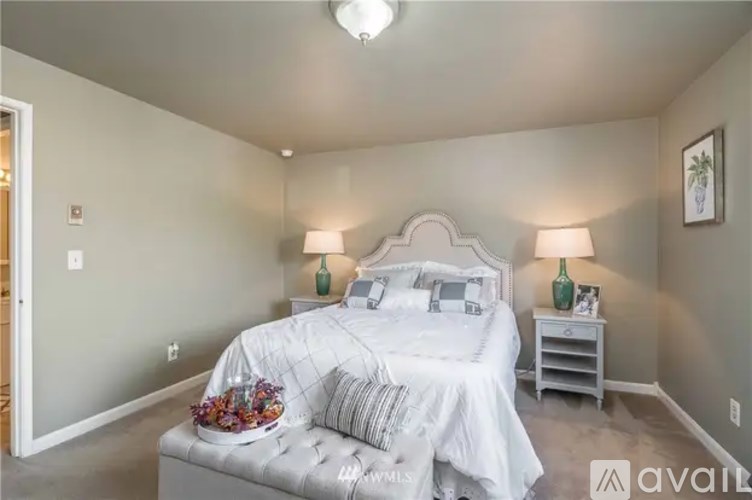 A bedroom with a large bed and two lamps.