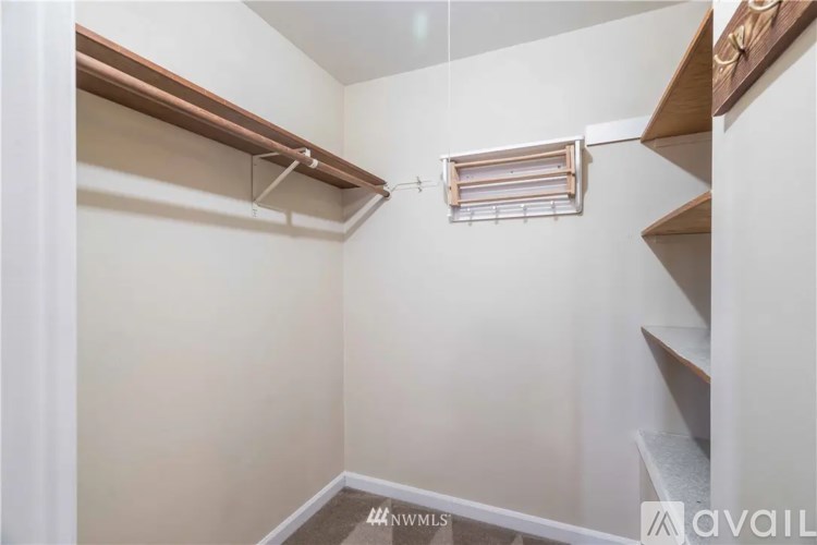 A small, white closet with a shelf and a window.