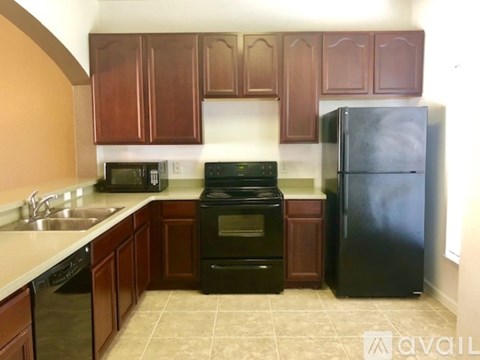 A kitchen with brown cabinets and black appliances.