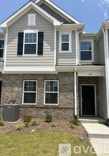 A two-story house with a grey and white exterior and a black door.