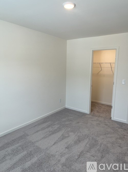 A room with a carpeted floor and a doorway leading to another room.