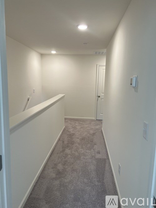 A long hallway with a carpeted floor and white walls.
