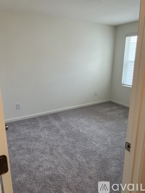 A room with a carpeted floor and a door on the left.