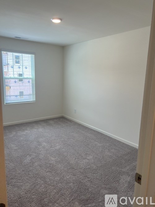 A room with a carpeted floor and a window with blinds.
