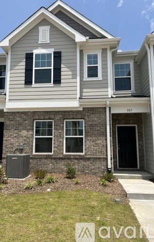 A two-story house with a grey and white exterior and a black door.