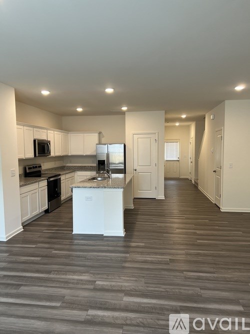 A kitchen with white cabinets and a white island in the middle of a room with wood flooring.