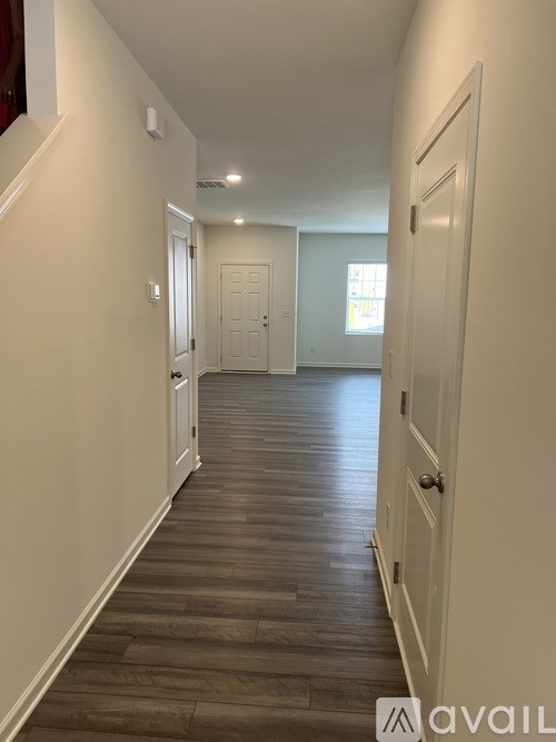 A long hallway with white walls and wood flooring.