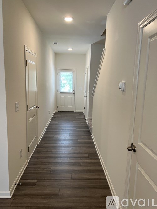 A long hallway with wood floors and white walls.