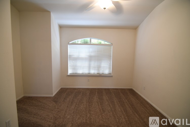 A room with a window covered by white blinds and a ceiling fan.