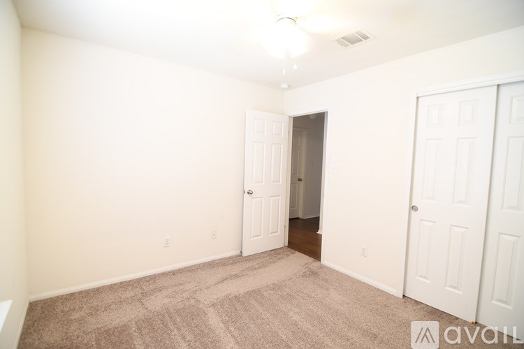 A room with a carpeted floor and two doors.