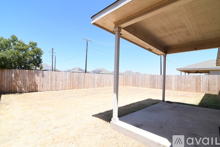 A backyard with a wooden fence and a covered patio area.