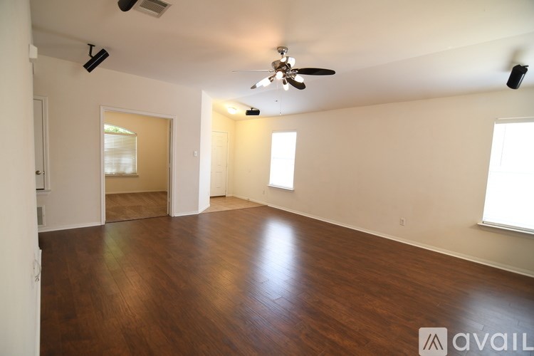 A spacious room with wooden floors and a ceiling fan.