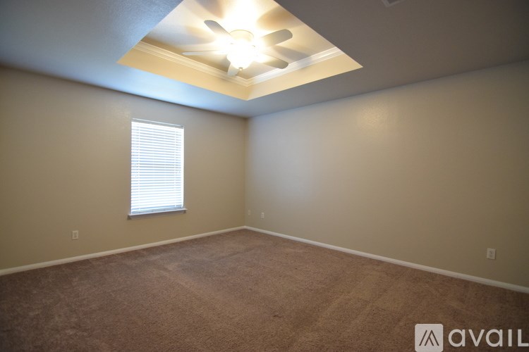 A spacious room with wooden floors and a ceiling fan.
