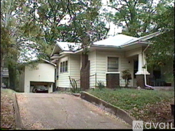 A house with a white garage door is surrounded by trees.